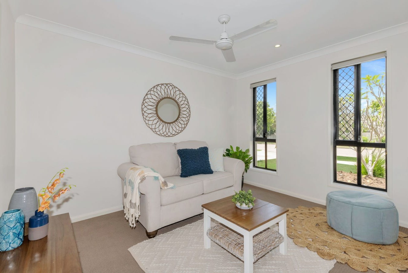 Neutral-toned lounge room with a white loveseat, natural wood coffee table, and soft decor accents, from Australia's leading disability accommodation provider.