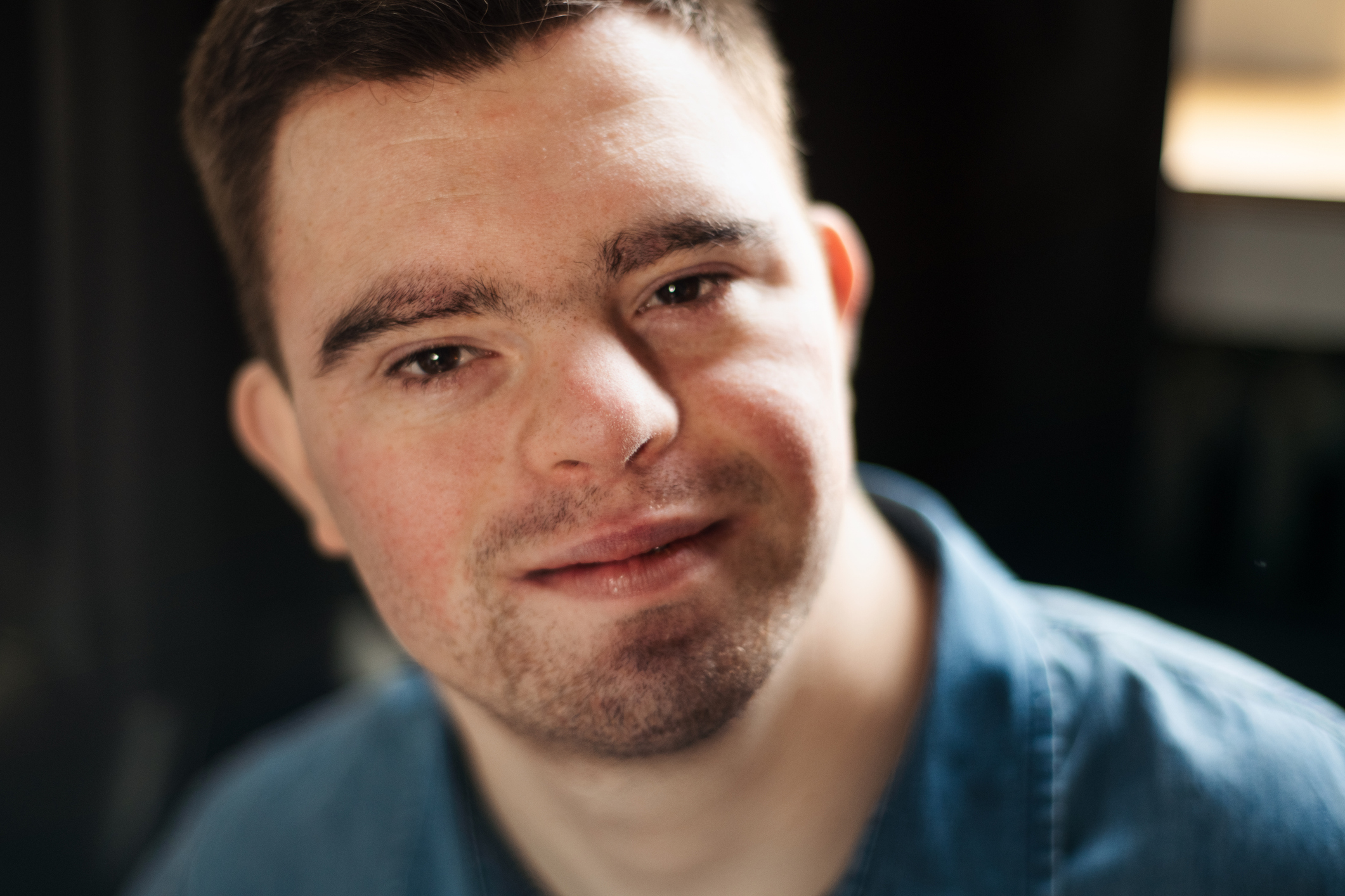 Cheerful young man with Down syndrome looking at camera.