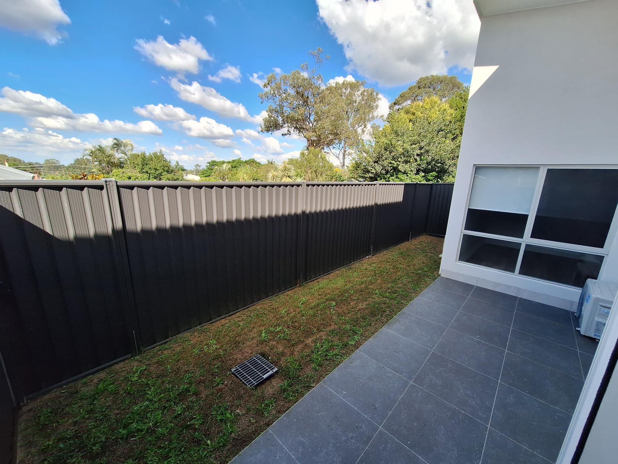 Private, accessible backyard of a SIL in Brand New HPS Villas in Brassall, 14 Hayes St, Brassall Qld 4305, featuring paved patio, secure fencing, and green lawn, part of Australia’s leading disability accommodation provider.