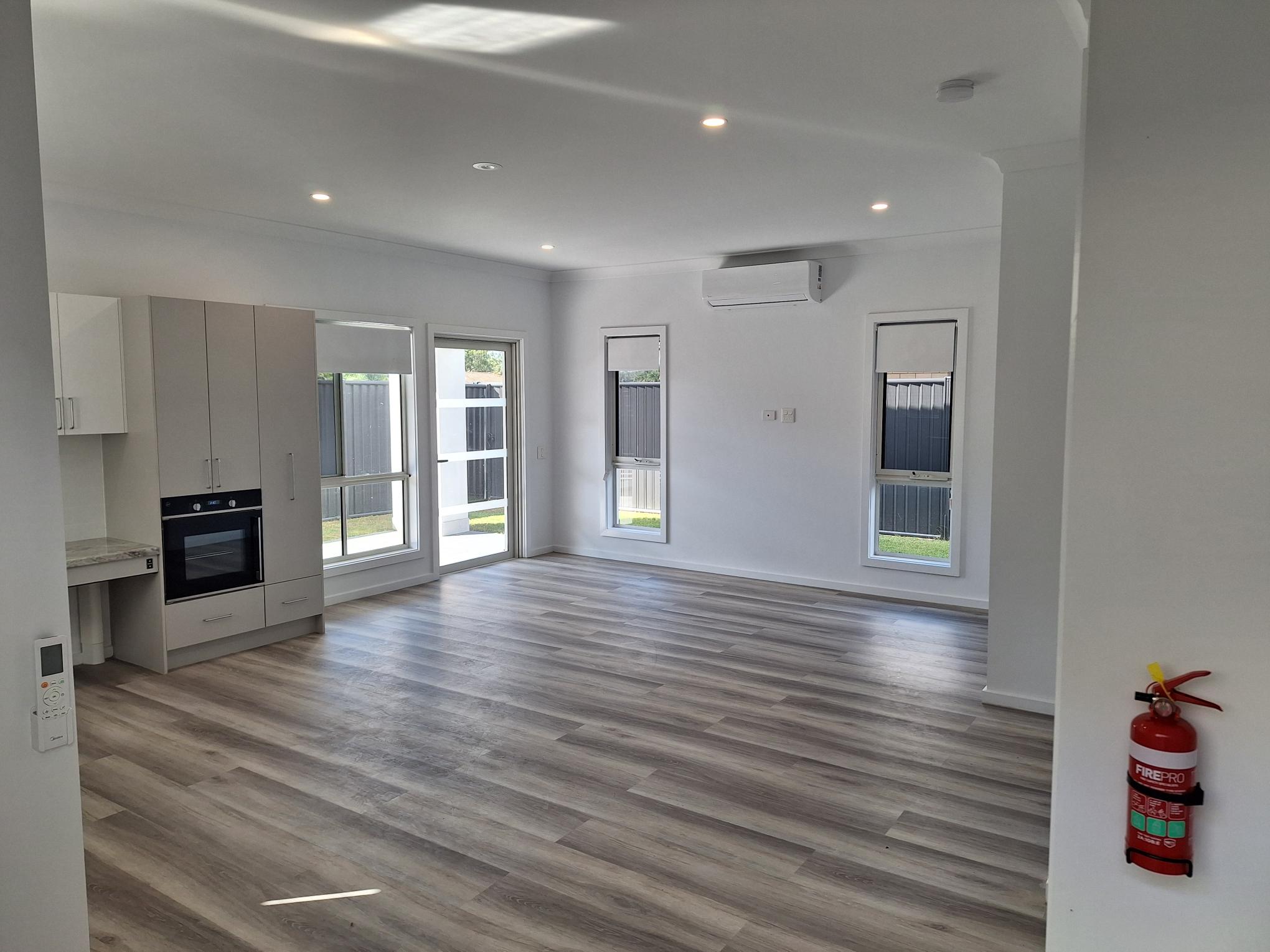 Spacious, accessible open-plan living area in a SIL in Brand New HPS Villas in Brassall, 14 Hayes St, Brassall Qld 4305, featuring light wood flooring, modern kitchenette, and safety features, part of Australia’s leading disability accommodation provider.