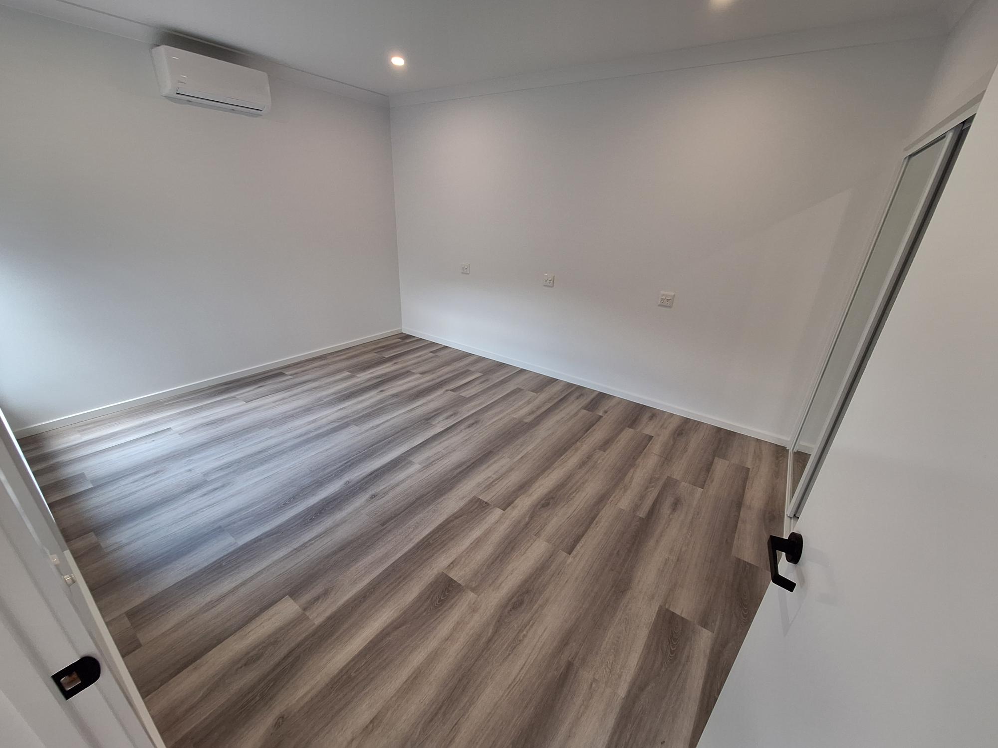 Spacious, accessible room in a SIL in Brand New HPS Villas in Brassall, 14 Hayes St, Brassall Qld 4305, featuring light wood flooring, wall-mounted air conditioning, and wide doorways, part of Australia’s leading disability accommodation provider.