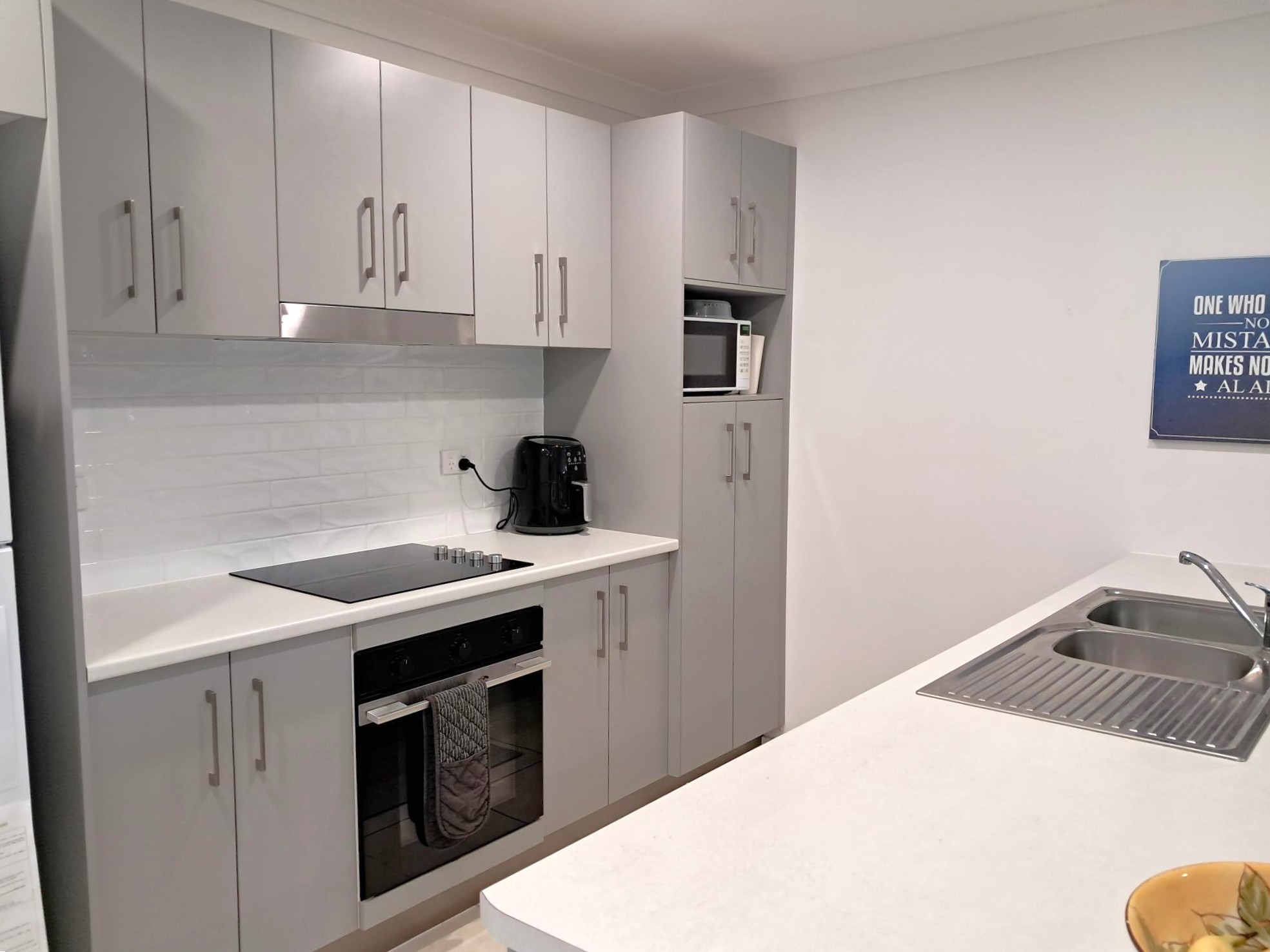 Contemporary kitchen with sleek grey cabinetry, built-in oven, microwave, and dual sink, designed for accessible living, from Australia's leading disability support provider.