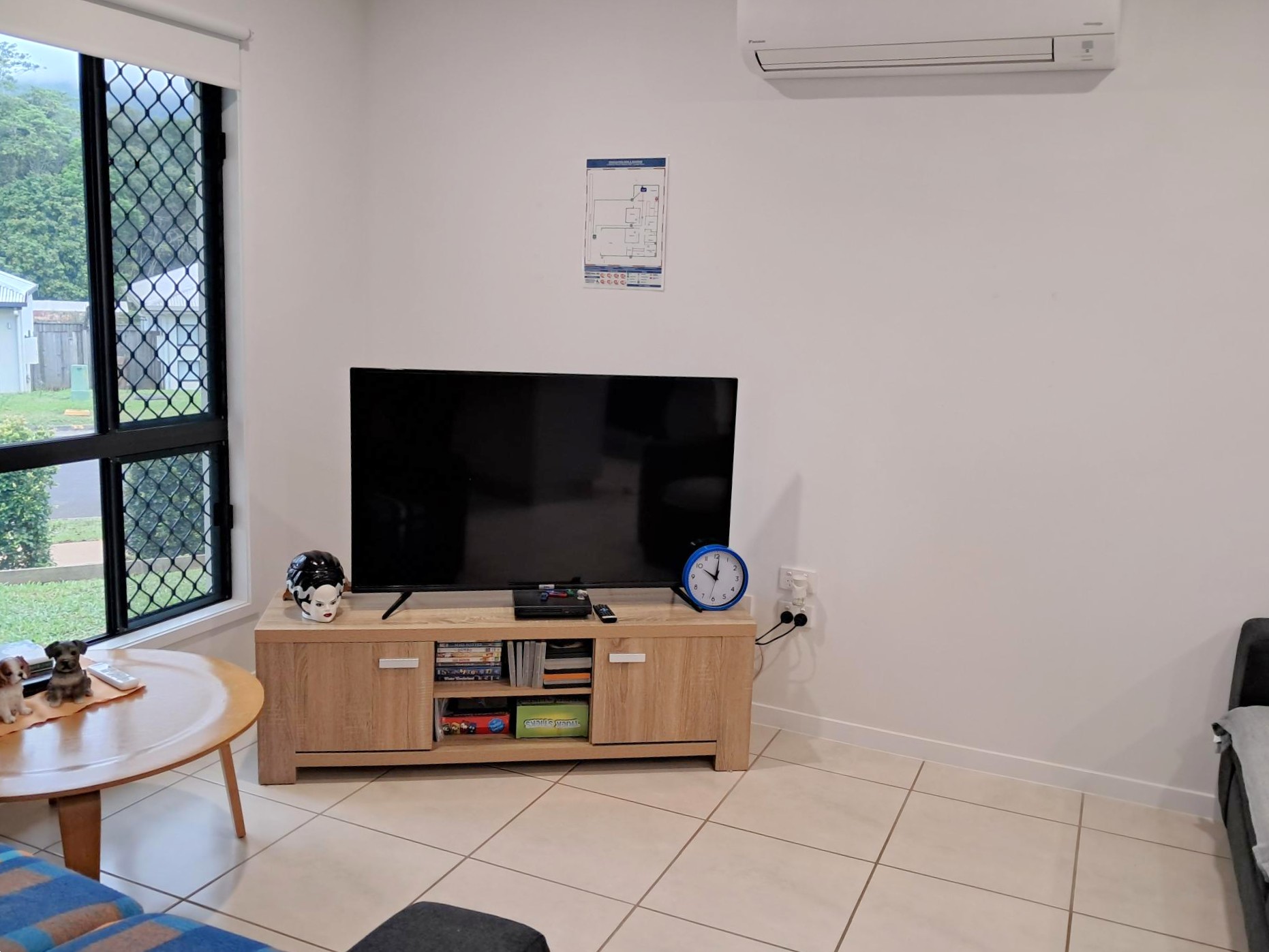 Air-conditioned lounge room with tiled floors, flat-screen TV on timber cabinet, and large window with security screen, from Australia's leading disability accommodation provider.
