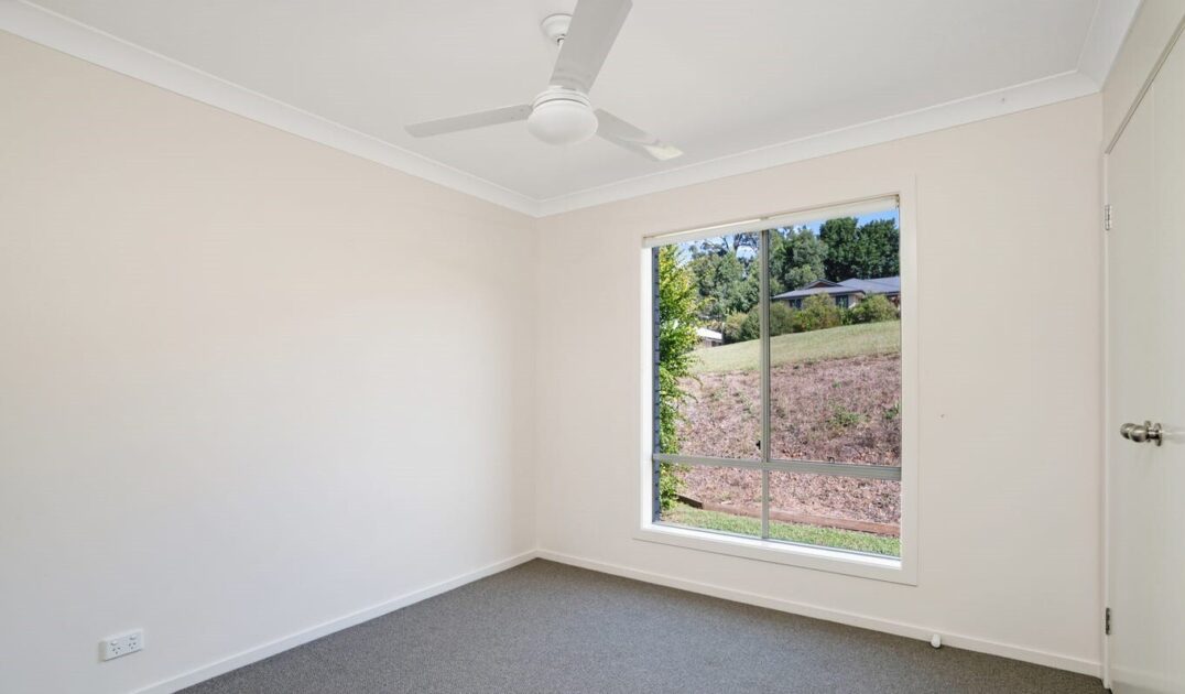 Empty bedroom with large window and white ceiling fan, designed for natural light and comfort, from Australia's leading disability care provider.