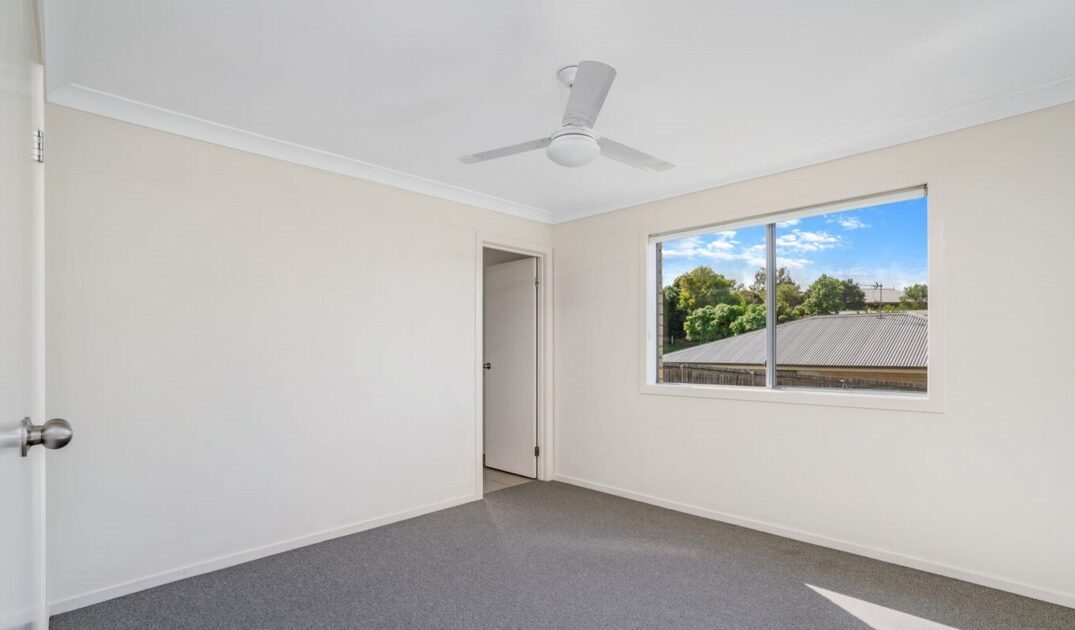 Bright modern bedroom with ceiling fan and large window overlooking greenery in Peaceful Southside from Australia's leading disability care provider.