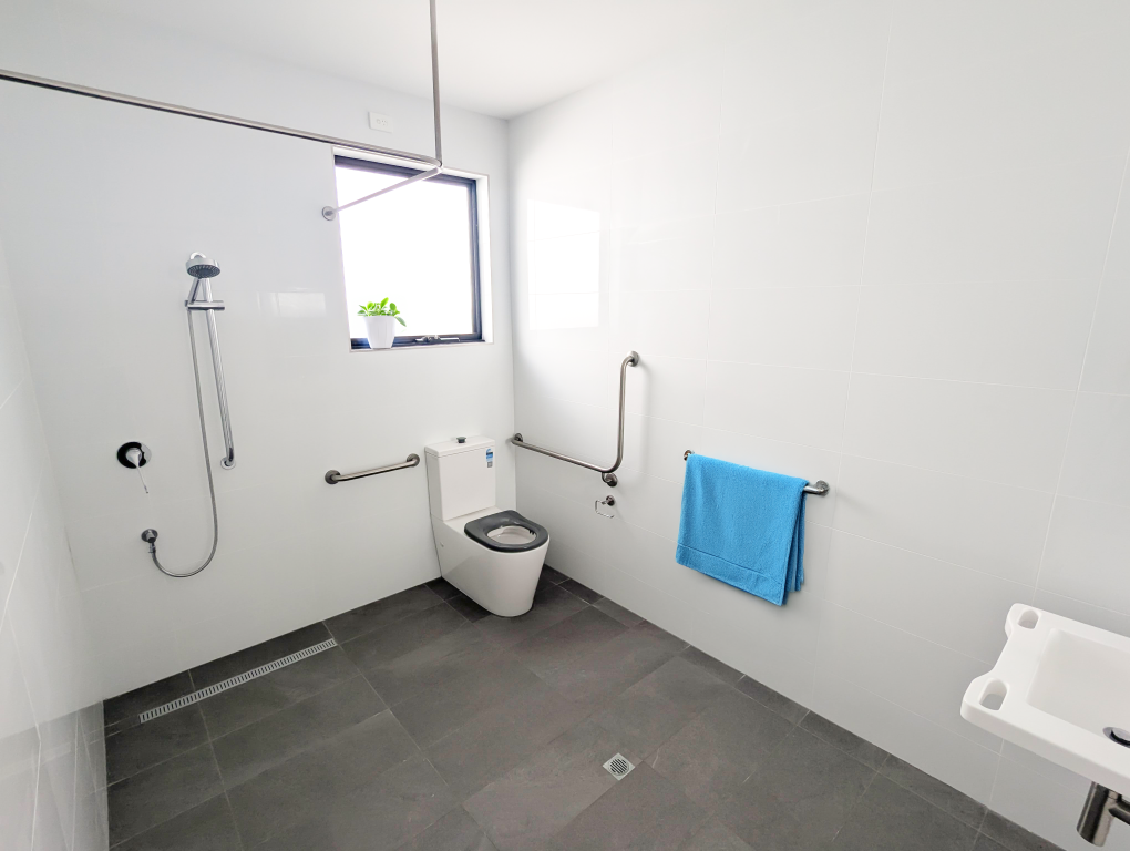 Fully accessible bathroom in our Beautiful Brand New SDA Home in Christie Beach, designed for safety and independence with grab rails, roll-in shower, and wall-mounted fixtures by Australia’s leading disability accommodation provider.