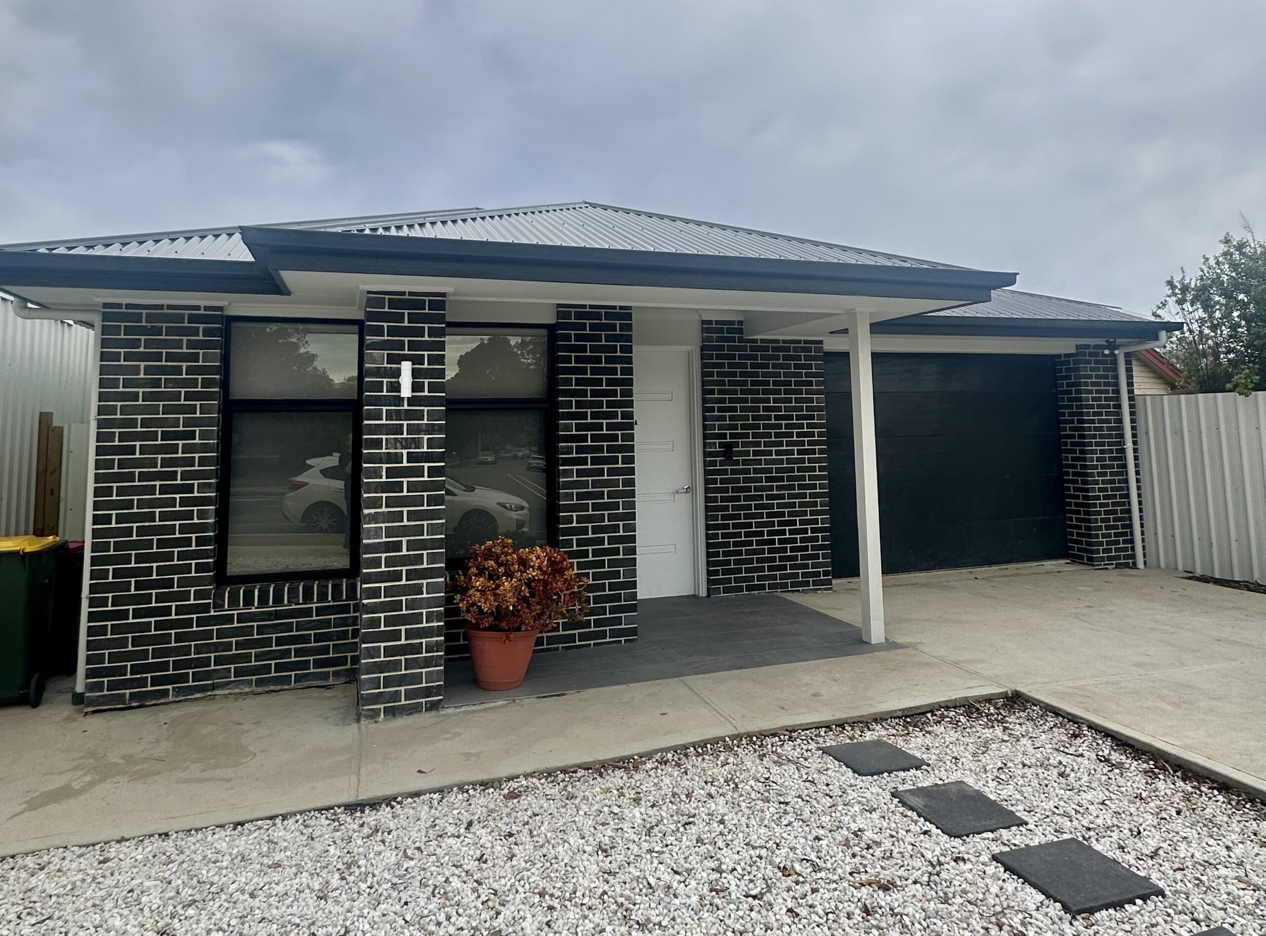 Modern Specialist Disability Accommodation (SDA) Home in 7A Galloway Road, Christie Beach, Australia, featuring black brick facade, accessible entry, and minimalist landscaping, part of Australia’s leading disability accommodation provider.