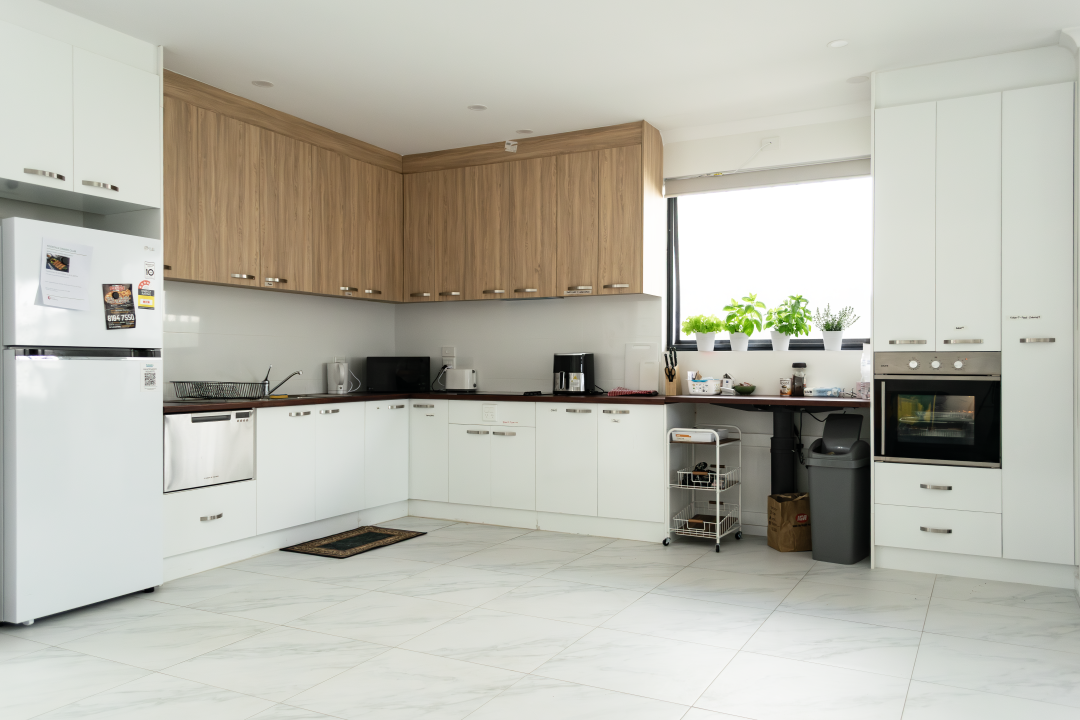 Modern, accessible kitchen in a Beautiful Brand New SDA Home in Christie Beach, featuring white and wood cabinets, marble-effect tiles, and stainless steel appliances, part of Australia’s leading disability accommodation provider.