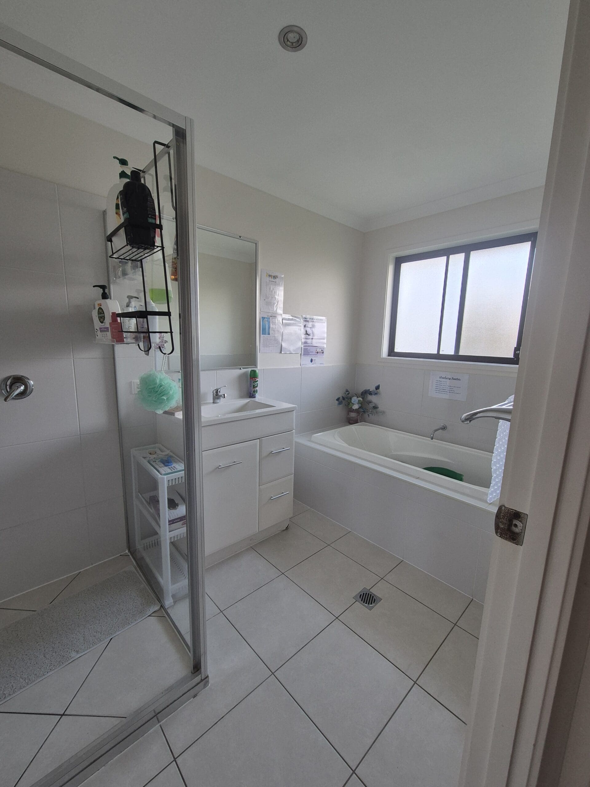 Accessible bathroom in a Warm and Inviting SIL Home in Parkhurst, 32 Vermont Drive, Parkhurst Qld 4702, featuring walk-in shower, bath, and safety signage, part of Australia’s leading disability accommodation provider.