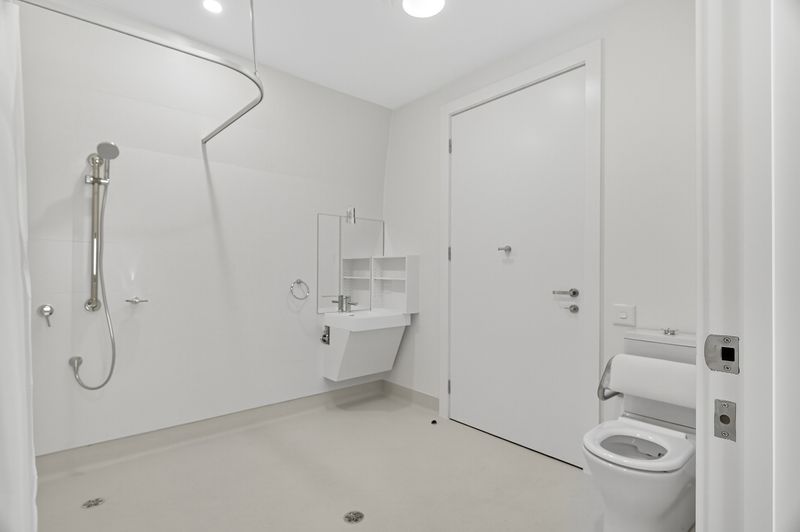 Accessible bathroom in a High Physical Support SDA Villa in 3 1B Gladstone Street Fullarton SA 5063, featuring roll-in shower, wall-mounted sink, and floor drain, part of Australia’s leading disability accommodation provider.