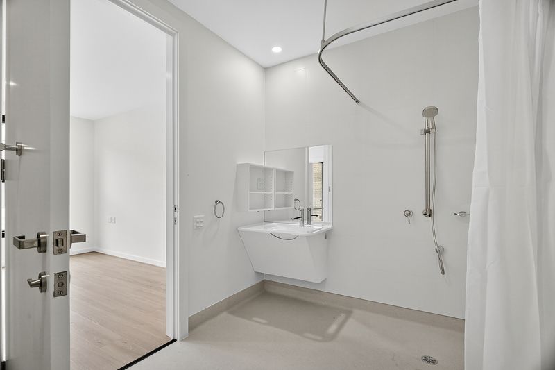 Accessible bathroom in a High Physical Support SDA Villa in Fullarton, 3 1B Gladstone Street SA 5063, featuring roll-in shower, wall-mounted sink, and ceiling hoist-ready rail, part of Australia’s leading disability accommodation provider.