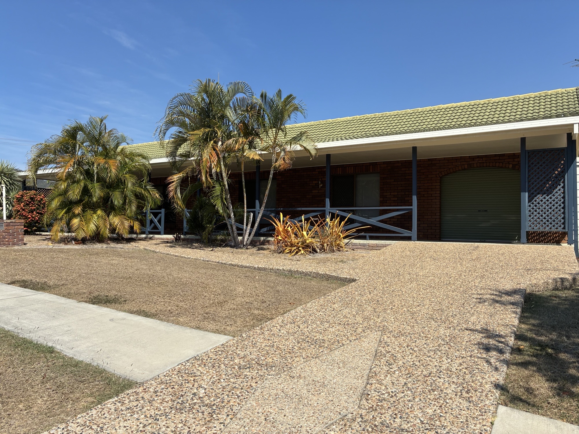 Welcoming exterior of a Spacious SIL Home in the Heart of Rockhampton, 23 O'Shanesy Street, Koongal Qld 4701, featuring accessible driveway, covered porch, and tropical landscaping, part of Australia’s leading disability accommodation provider.