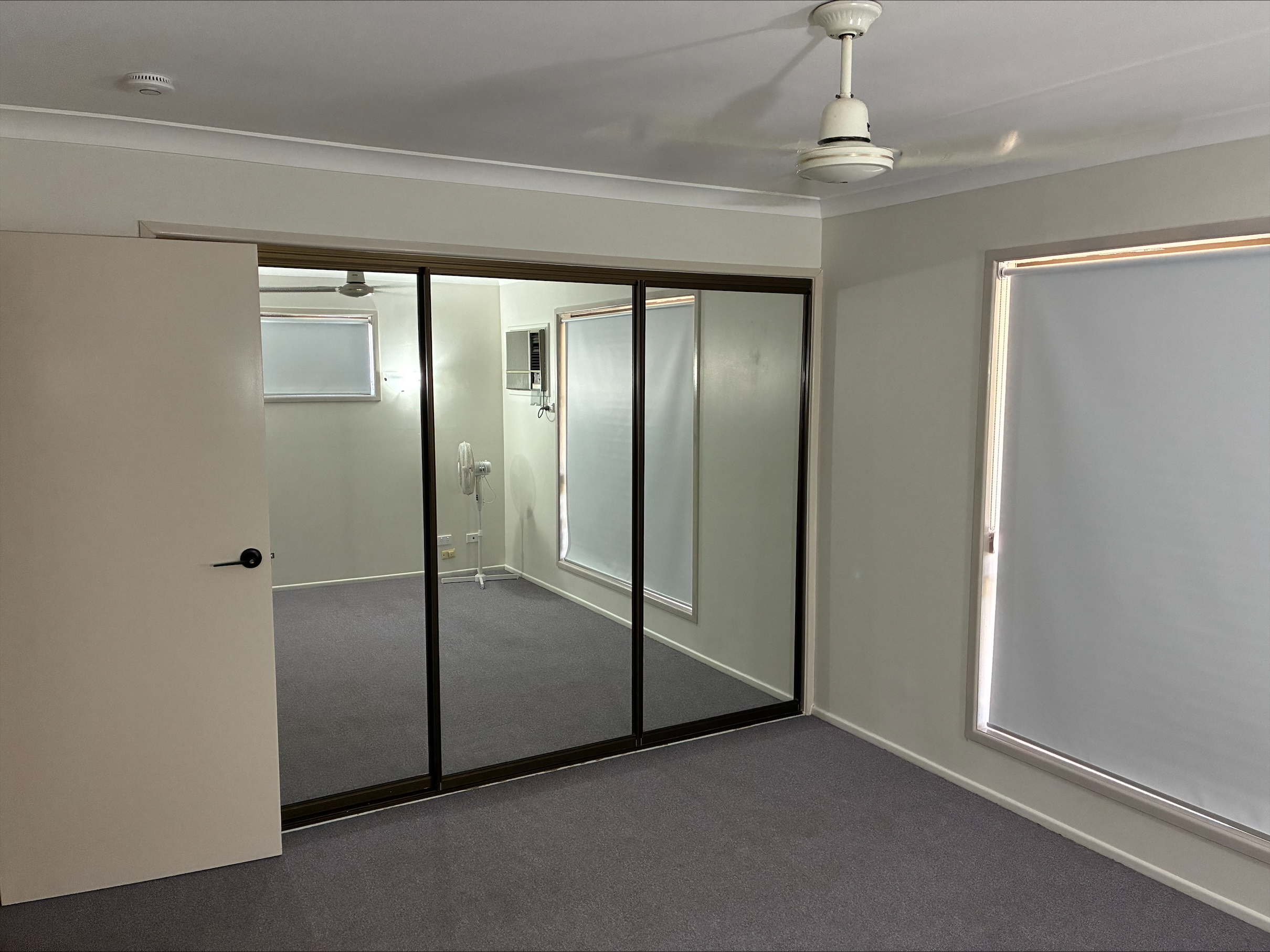 Spacious, accessible bedroom in a Spacious SIL Home in the Heart of Rockhampton, 23 O'Shanesy Street, Koongal Qld 4701, featuring grey carpet, mirrored wardrobes, and wide doorways, part of Australia’s leading disability accommodation provider.