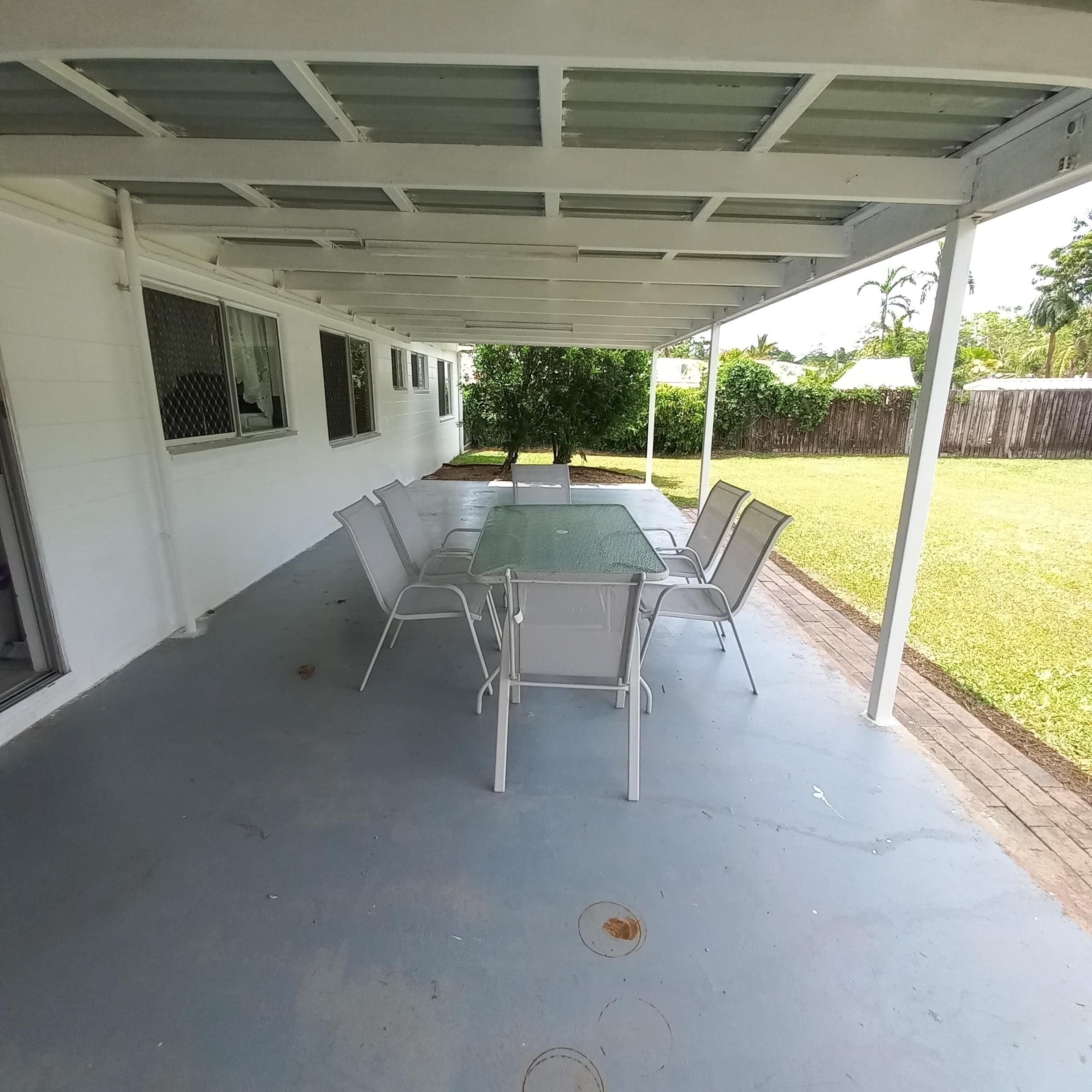 Spacious, accessible covered patio in a Spacious and Airy SIL home south of Cairns, 7 Royal Saxon Close, Mount Sheridan 4686, featuring outdoor dining set and garden views, part of Australia’s leading disability accommodation provider.