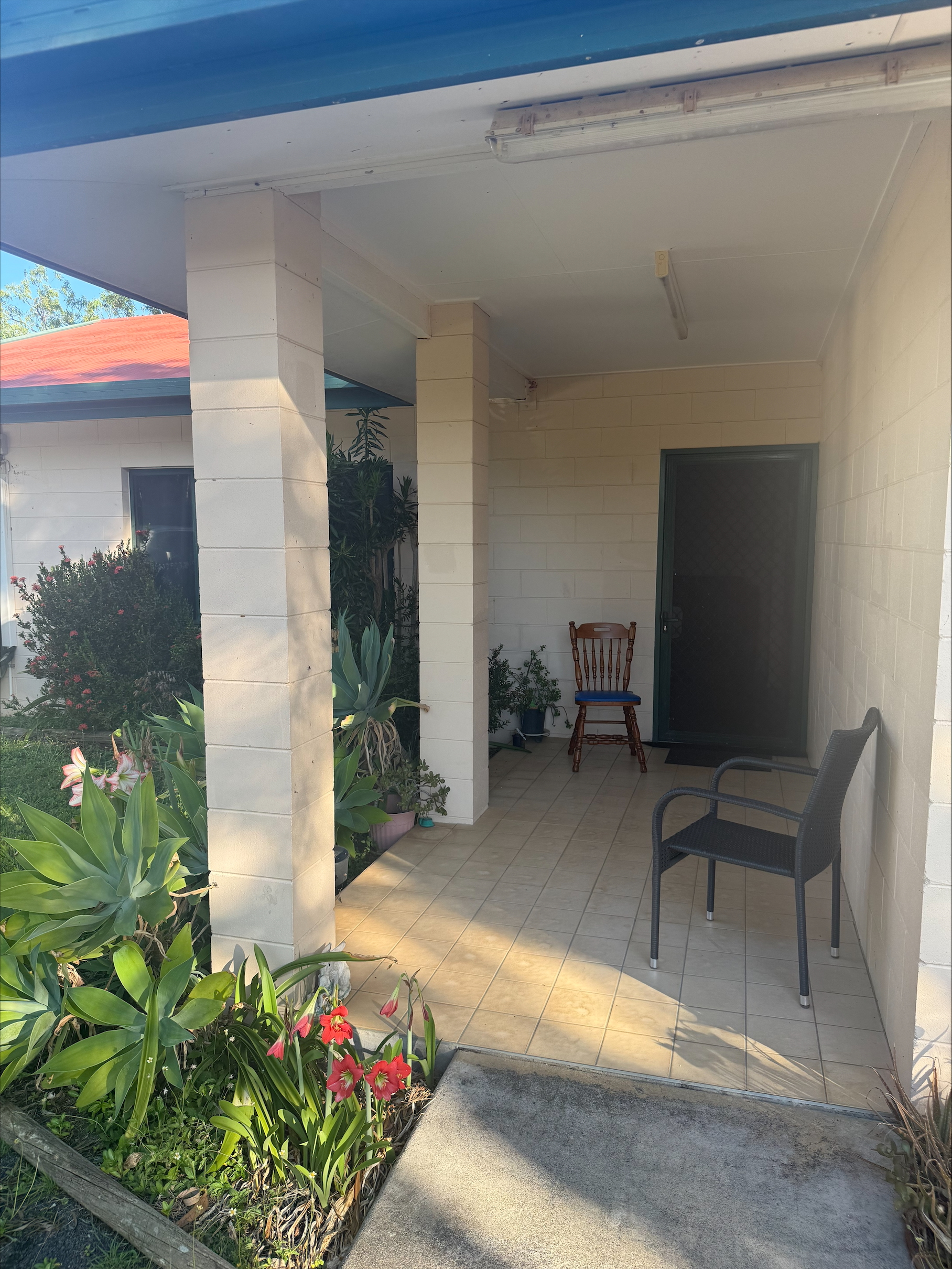 Accessible front porch of a Central and Roomy SIL home in Mareeba, 6 Kylie Close, Mareeba 4880, featuring covered seating, security door, and lush garden, part of Australia’s leading disability accommodation provider.