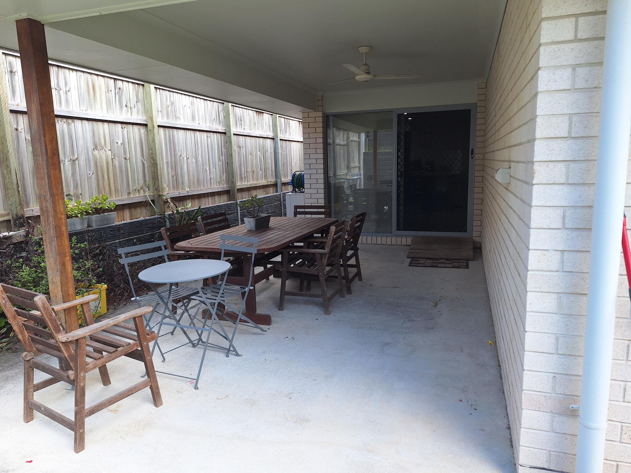 Accessible covered patio in Comfort of SIL in Tranquil Thornlands, featuring outdoor dining set, ceiling fan, and secure fencing, part of Australia’s leading disability accommodation provider.