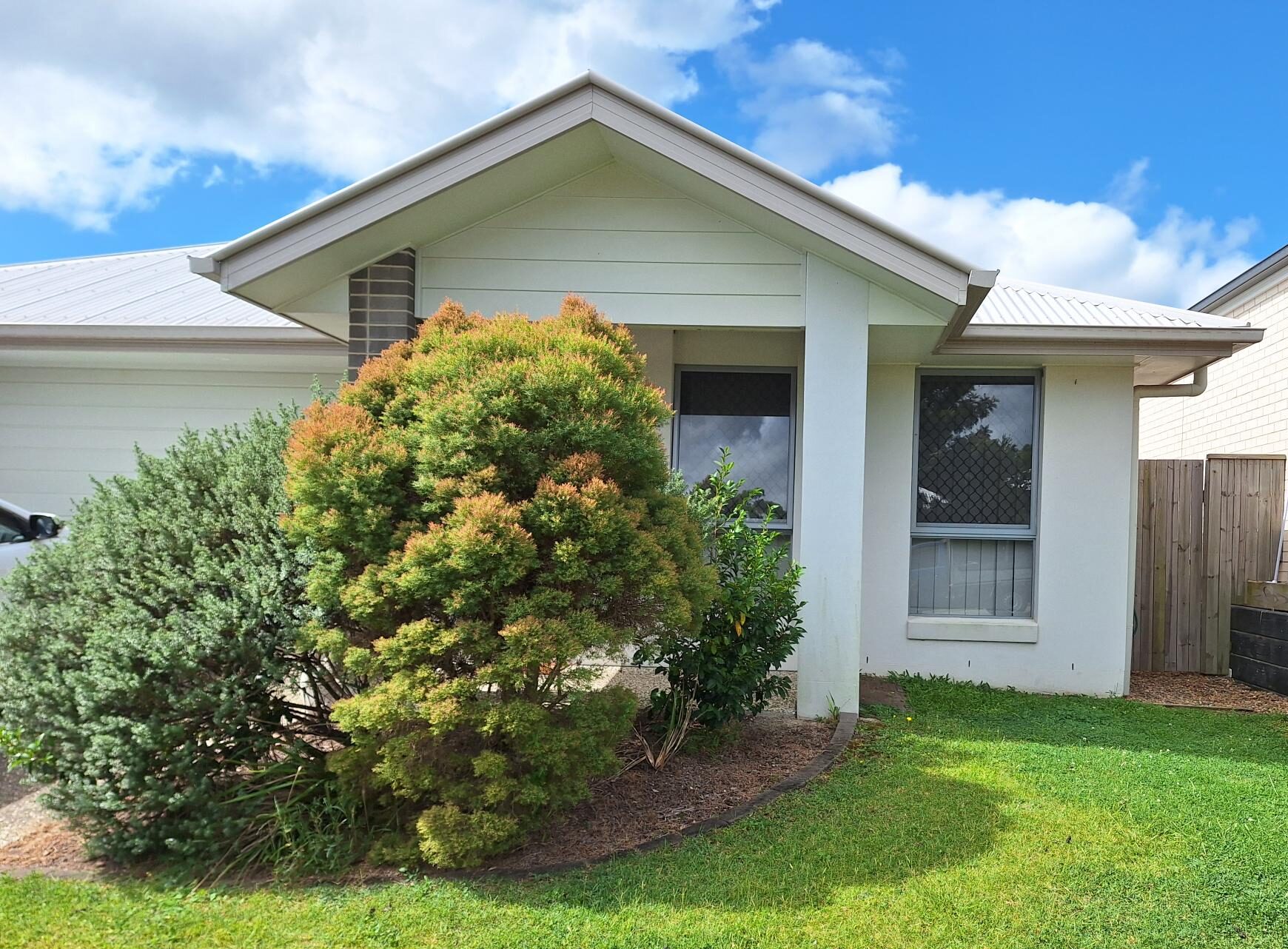 Welcoming exterior of Comfort of SIL in Tranquil Thornlands, featuring white facade, green lawn, and covered entry, part of Australia’s leading disability accommodation provider.